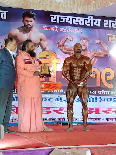 Sagar Ghaghre of SPARTANS Gym receiving a trophy at a state-level bodybuilding championship